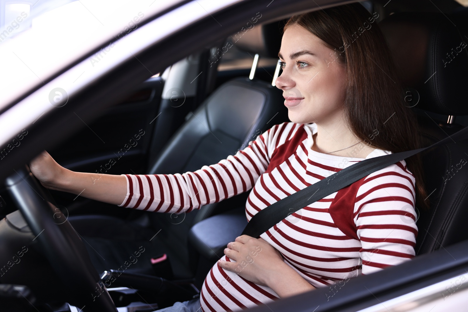 Photo of Pregnant woman with safety belt driving car