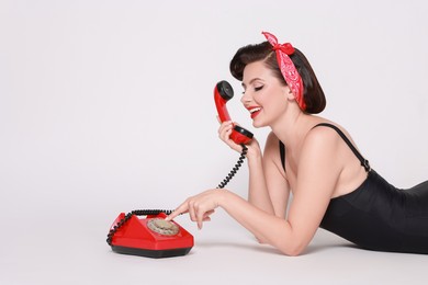 Photo of Pin-up woman with telephone on light background