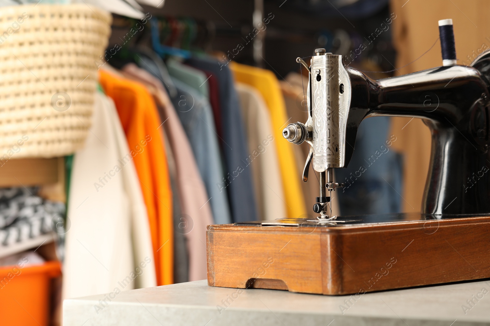 Photo of Vintage sewing machine with thread on white table in workshop, space for text