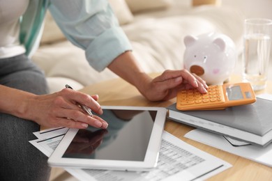 Photo of Budget planning. Woman using calculator and tablet at table indoors, closeup