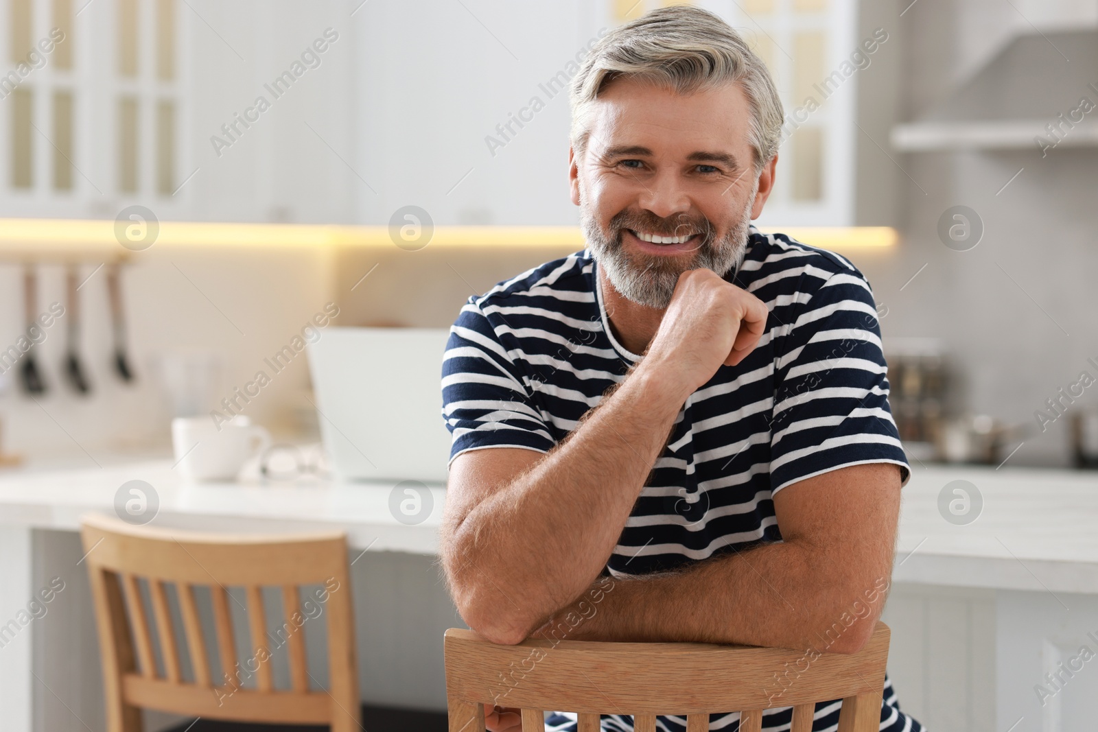 Photo of Happy middle aged man on chair in kitchen