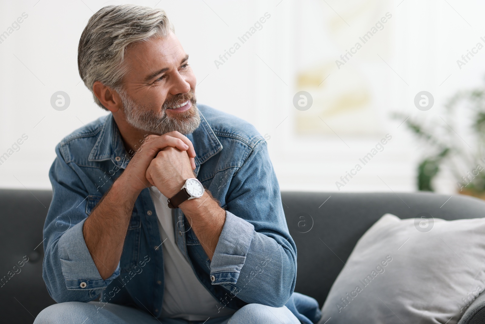 Photo of Happy middle aged man on sofa indoors, space for text