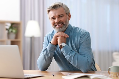 Photo of Happy middle aged man working at table indoors