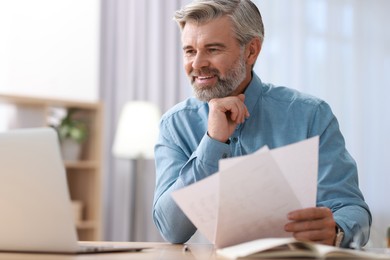 Photo of Happy middle aged man working at table indoors