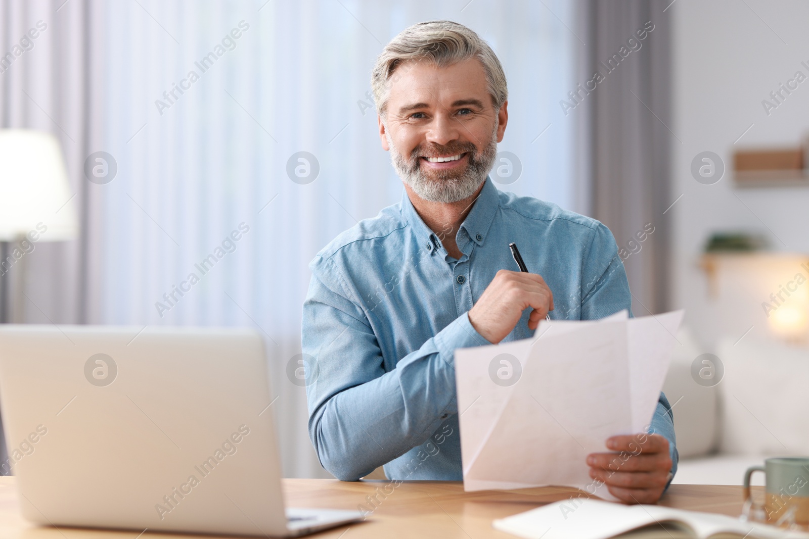 Photo of Happy middle aged man working at table indoors