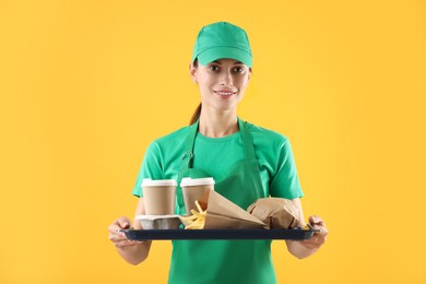 Photo of Fast-food worker holding tray with order on orange background