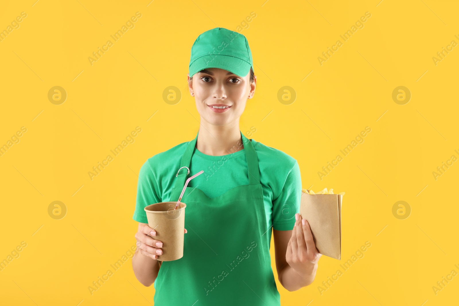 Photo of Fast-food worker with French fries and paper cup on orange background