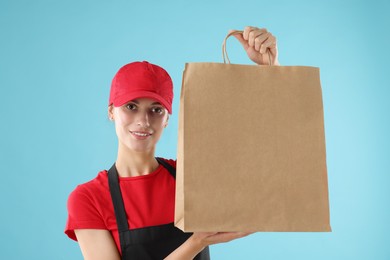 Photo of Fast-food worker with paper bag on light blue background