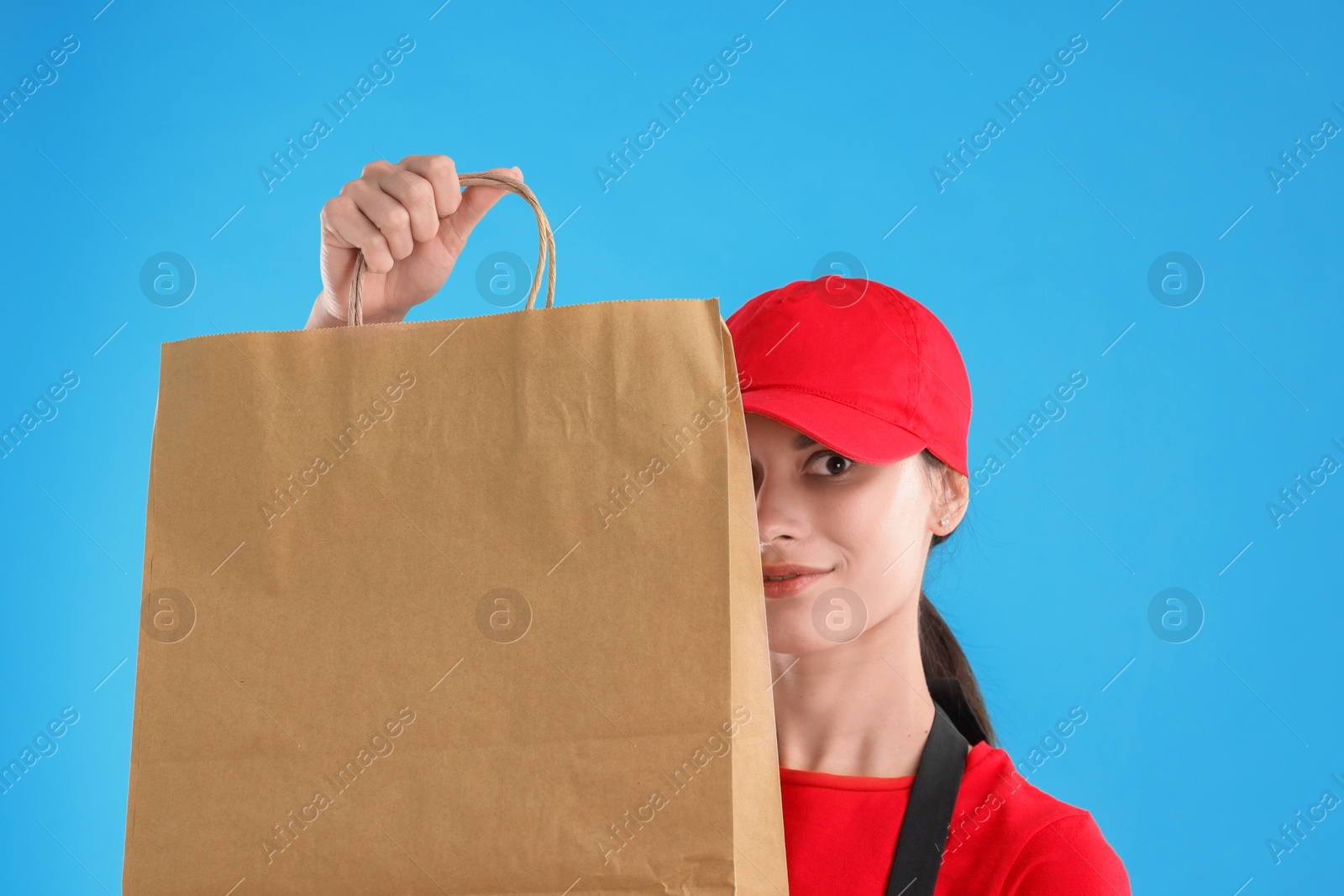 Photo of Fast-food worker with paper bag on light blue background