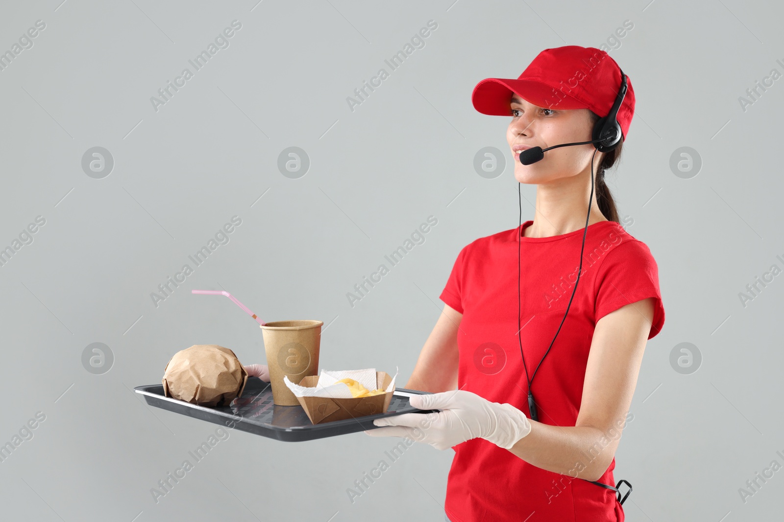 Photo of Fast-food worker holding tray with order on gray background,