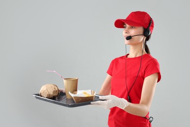 Photo of Fast-food worker holding tray with order on gray background,