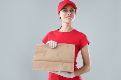 Photo of Fast-food worker with paper bag on gray background