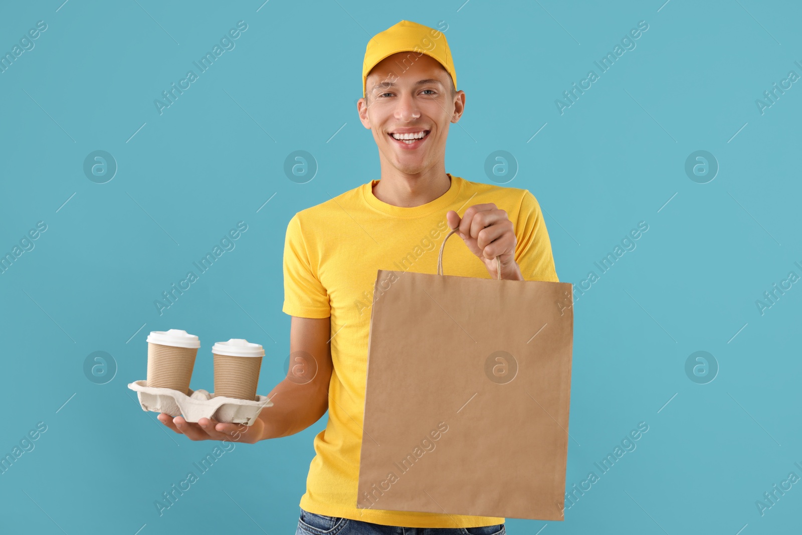 Photo of Fast-food worker with paper bag and cups on light blue background