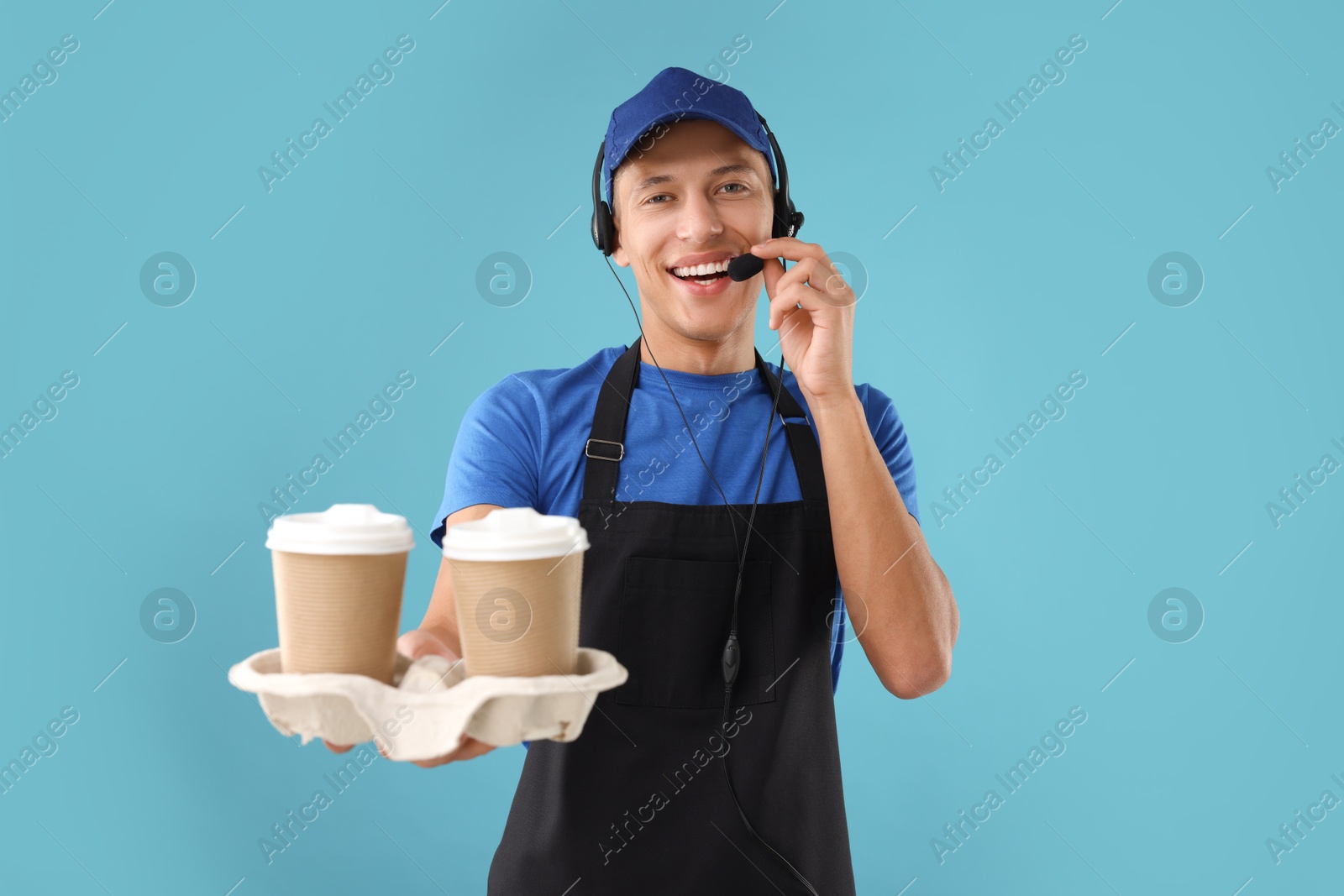 Photo of Fast-food worker with paper cups on light blue background