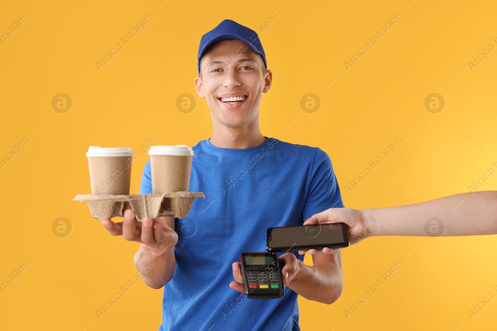 Photo of Fast-food worker taking payment from client via terminal on orange background, closeup