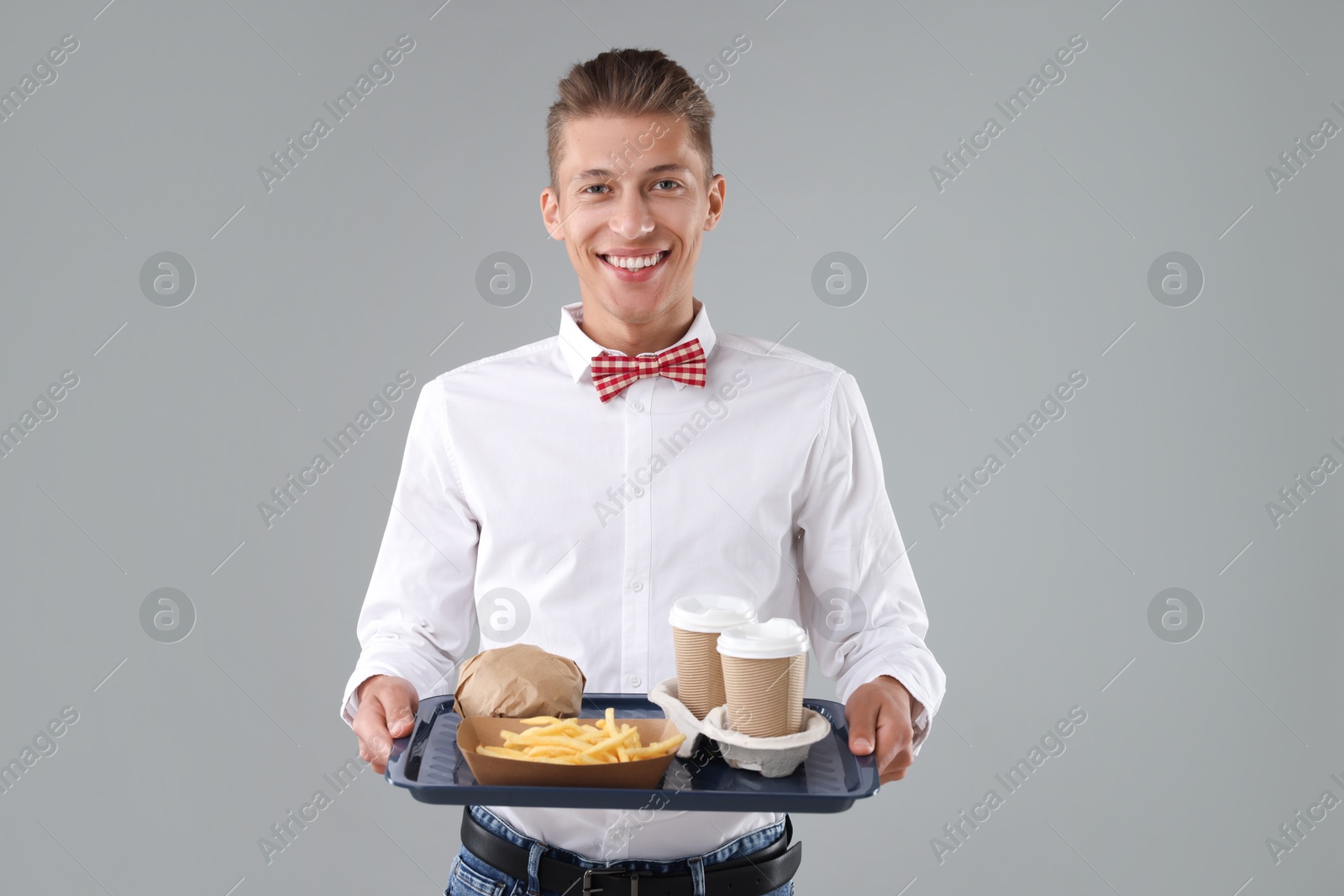 Photo of Fast-food worker holding tray with order on gray background