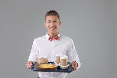 Photo of Fast-food worker holding tray with order on gray background