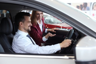 Happy saleswoman and client inside new car in salon