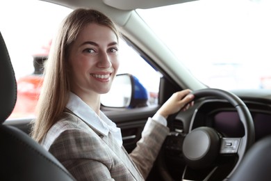 Photo of Young woman inside new car in salon