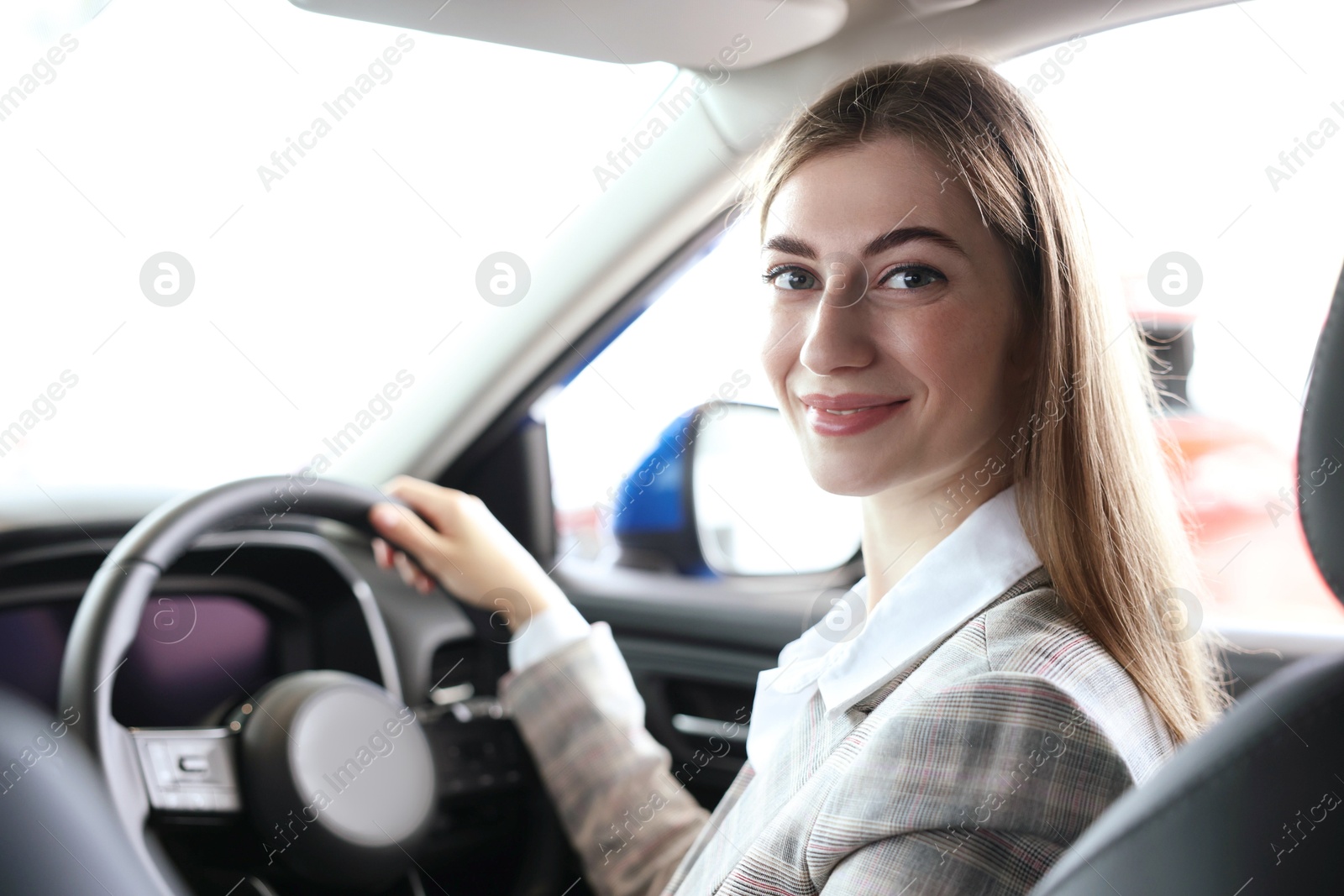 Photo of Young woman inside new car in salon