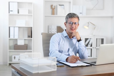 Photo of Portrait of smiling middle aged man at table in office