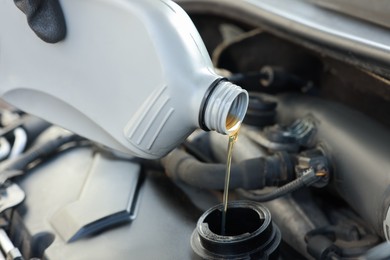 Photo of Pouring motor oil into car engine, closeup