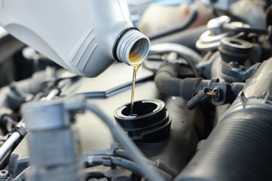 Photo of Pouring motor oil into car engine, closeup