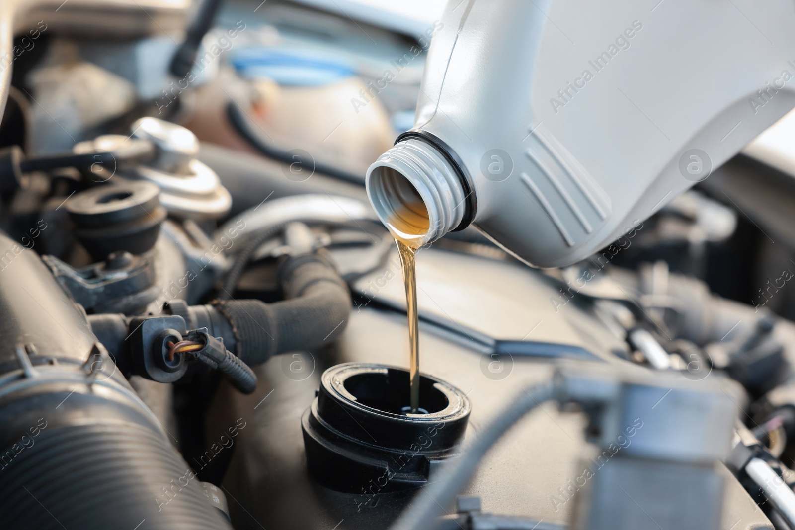 Photo of Pouring motor oil into car engine, closeup