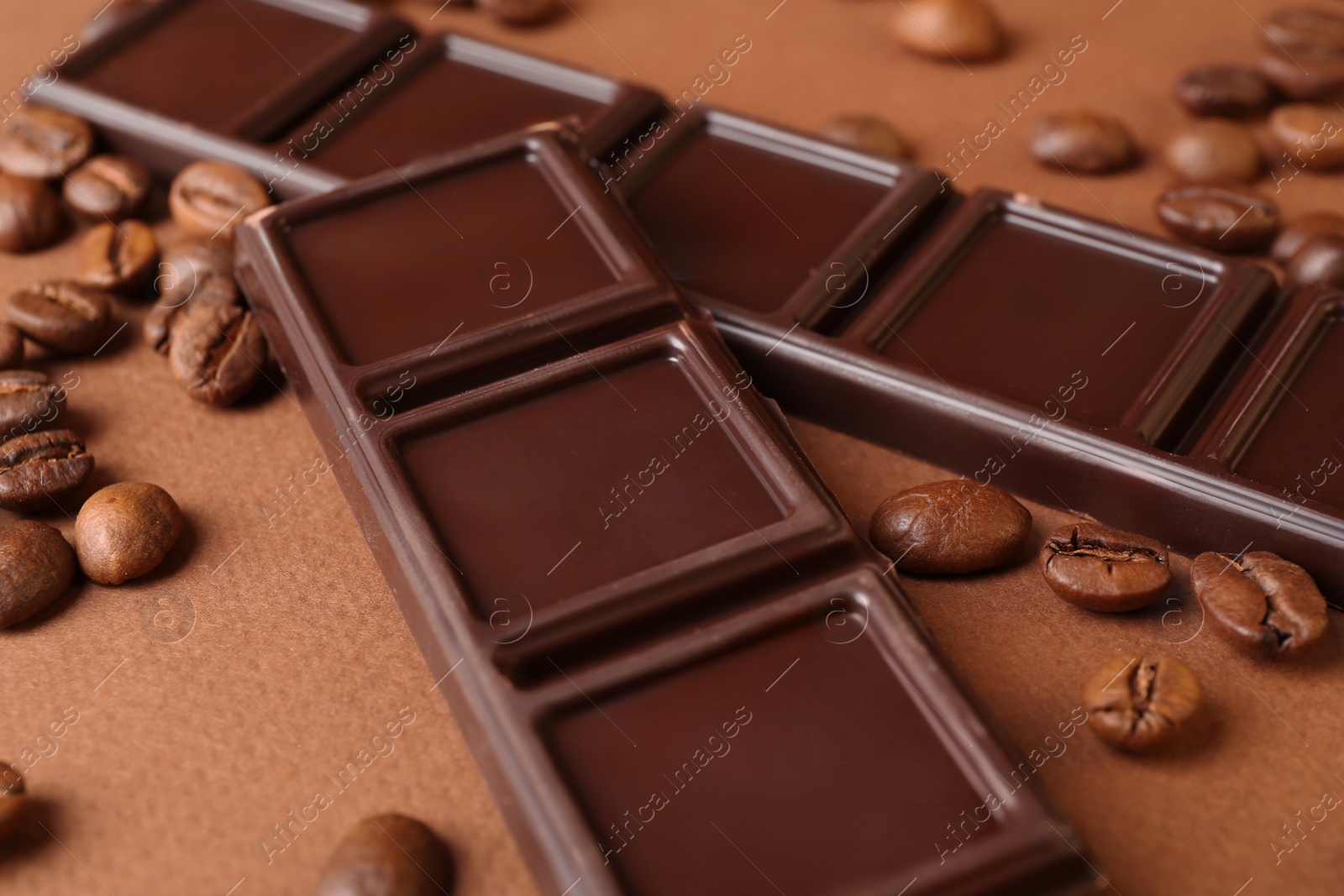 Photo of Pieces of tasty chocolate and coffee beans on brown background, closeup