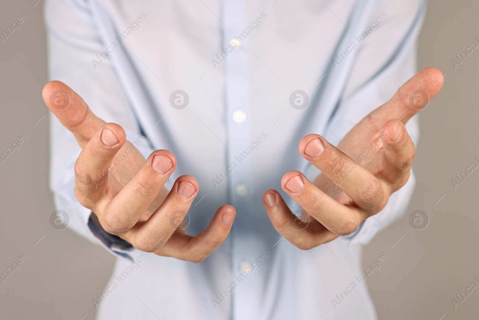 Photo of Man holding something on grey background, closeup