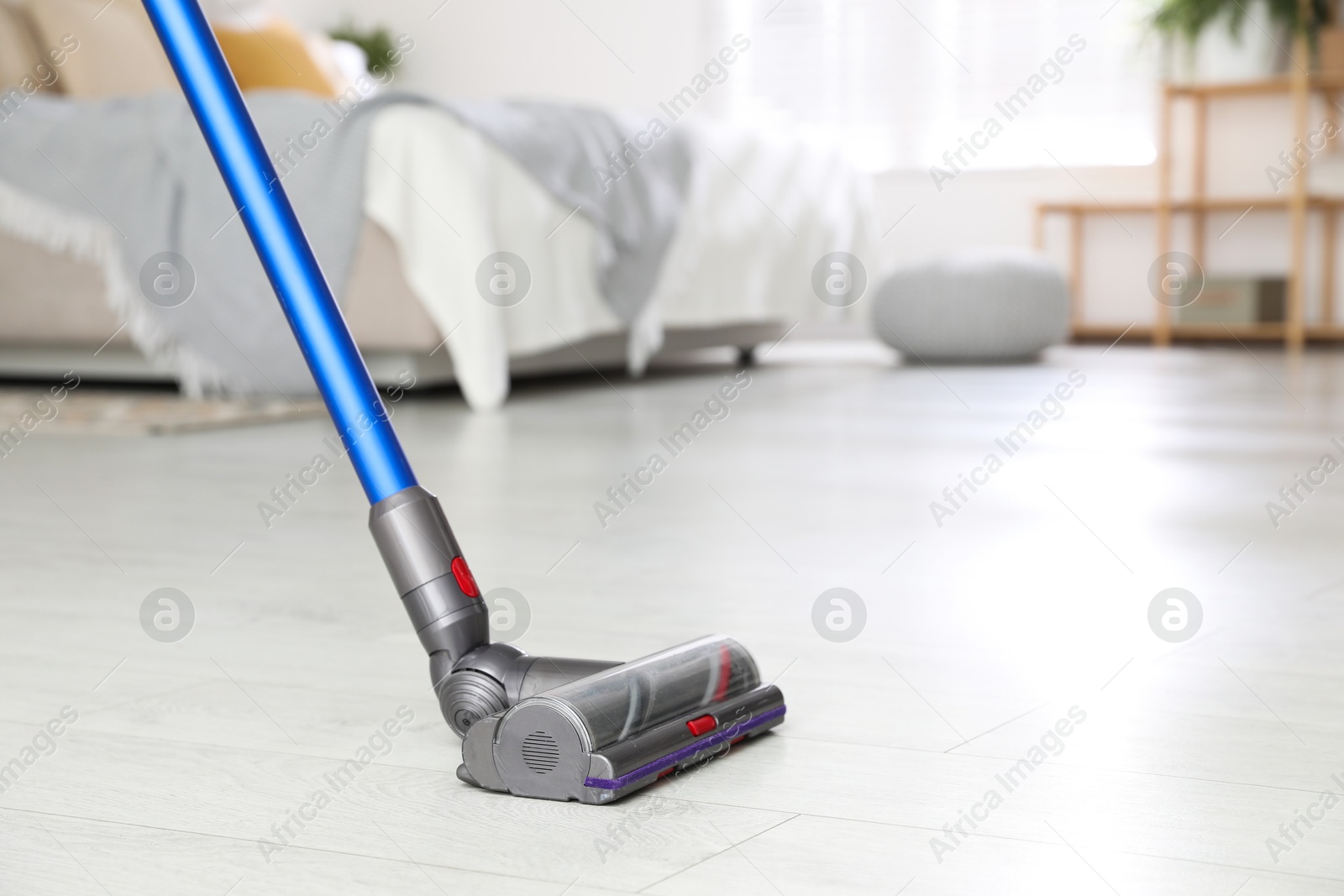 Photo of Cleaning floor with cordless vacuum cleaner indoors, closeup. Space for text