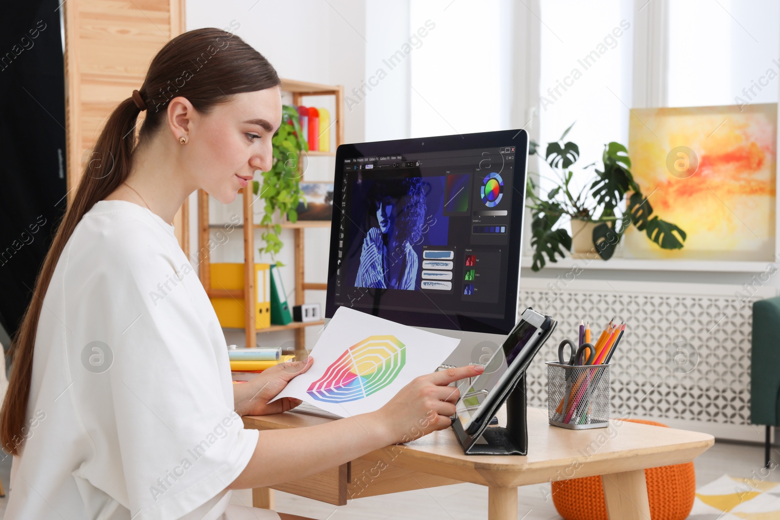 Photo of Designer working on tablet at wooden table indoors