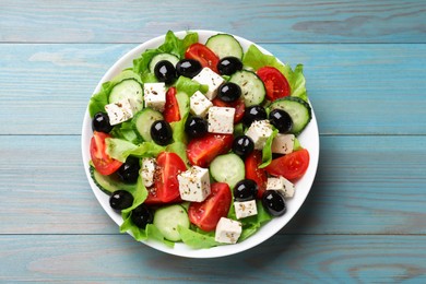 Photo of Delicious salad with feta cheese on light blue wooden table, top view