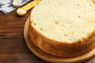 Photo of Tasty cut sponge cake on wooden table, closeup