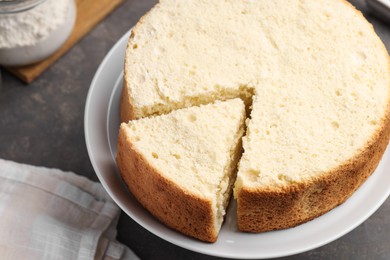 Photo of Tasty cut sponge cake on grey table, closeup