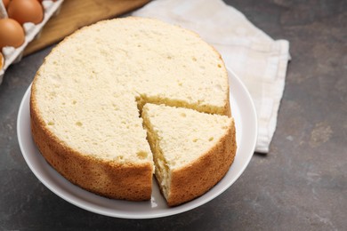 Tasty cut sponge cake on grey table