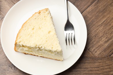 Photo of Piece of delicious sponge cake and fork on wooden table, top view