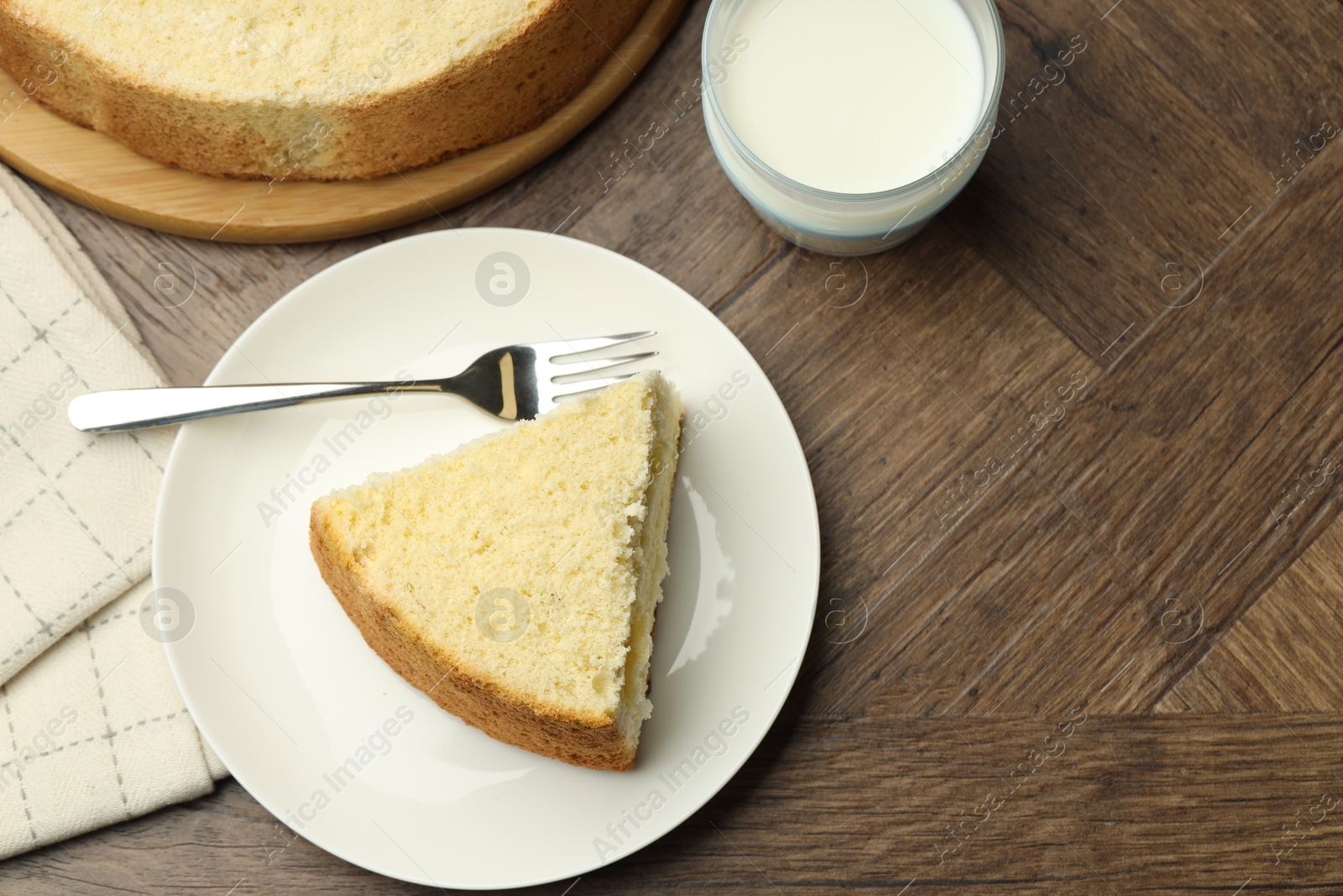 Photo of Piece of delicious sponge cake served on wooden table, flat lay. Space for text