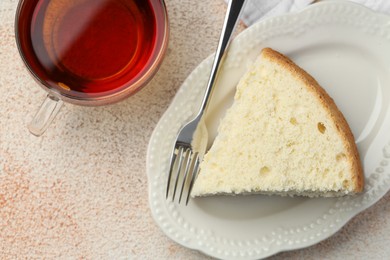 Photo of Piece of delicious sponge cake served on beige textured table, flat lay