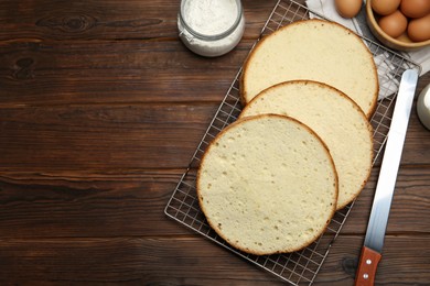 Photo of Delicious cut sponge cake, knife and ingredients on wooden table, flat lay. Space for text