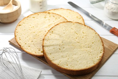 Photo of Delicious cut sponge cake and knife on white wooden table