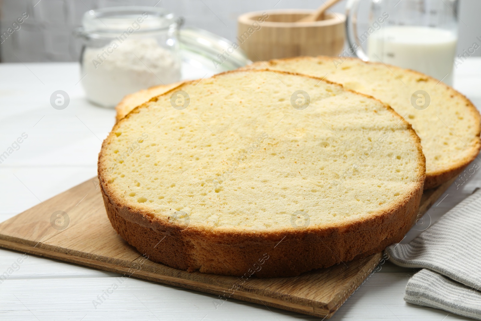 Photo of Delicious cut sponge cake on white wooden table