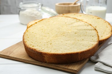 Photo of Delicious cut sponge cake on white wooden table