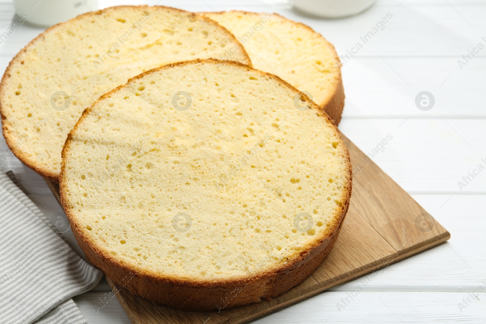 Photo of Delicious cut sponge cake on white wooden table