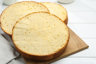 Photo of Delicious cut sponge cake on white wooden table