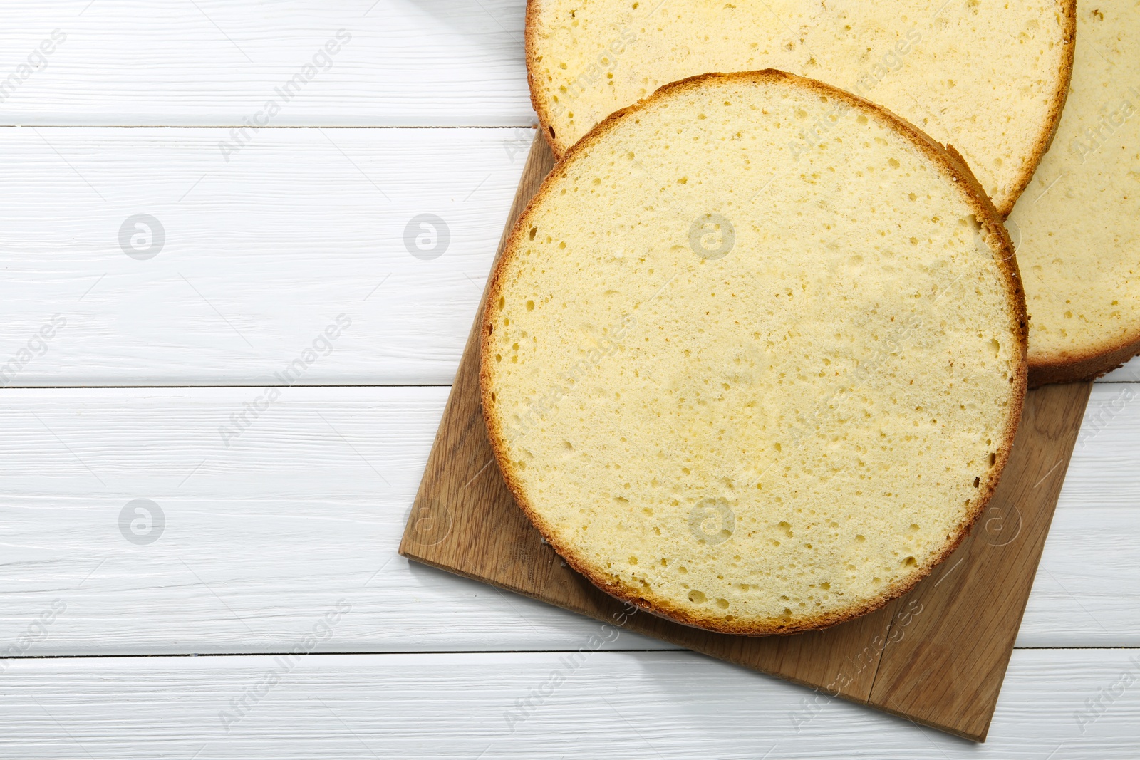 Photo of Delicious cut sponge cake on white wooden table, flat lay. Space for text