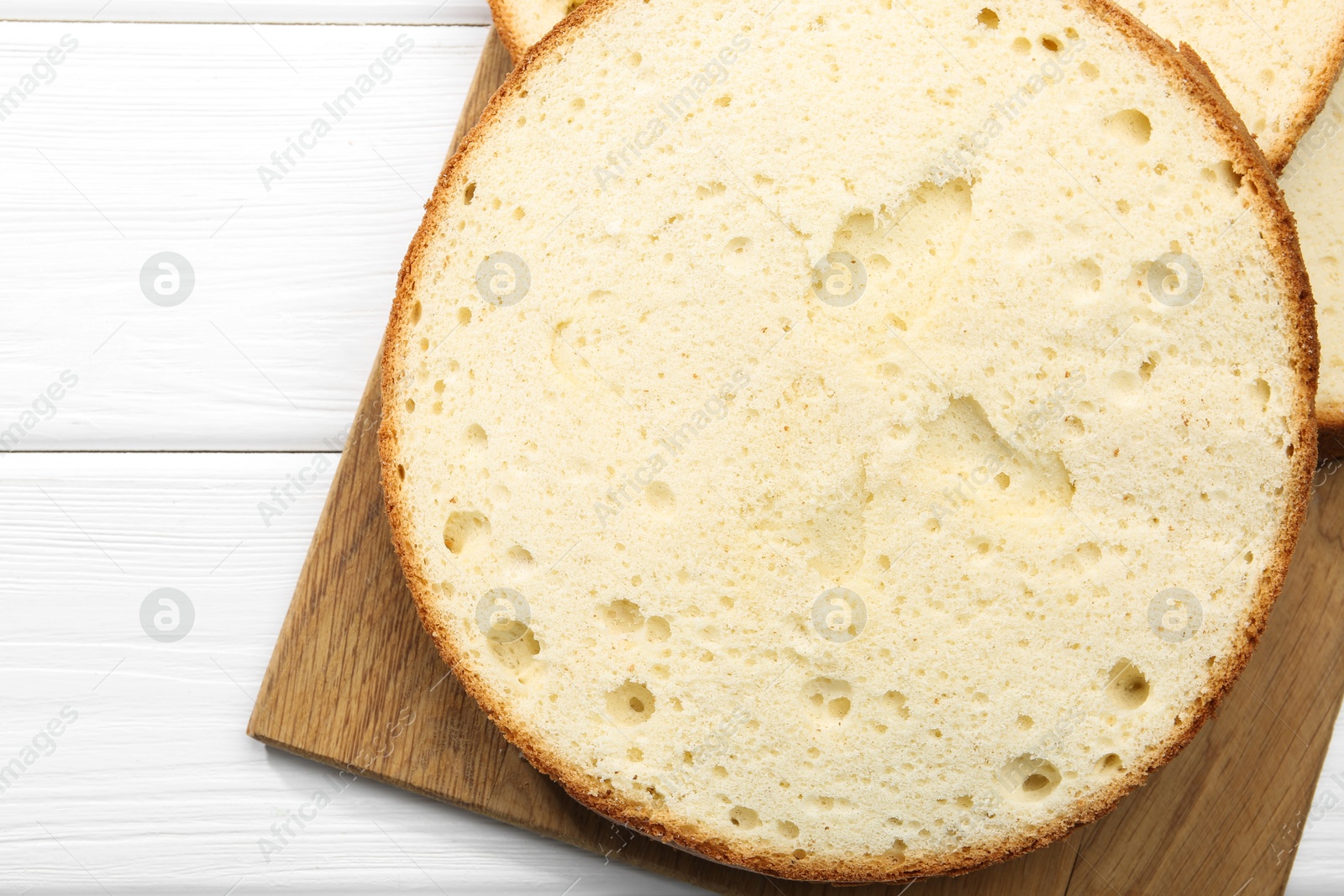 Photo of Delicious cut sponge cake on white wooden table, flat lay