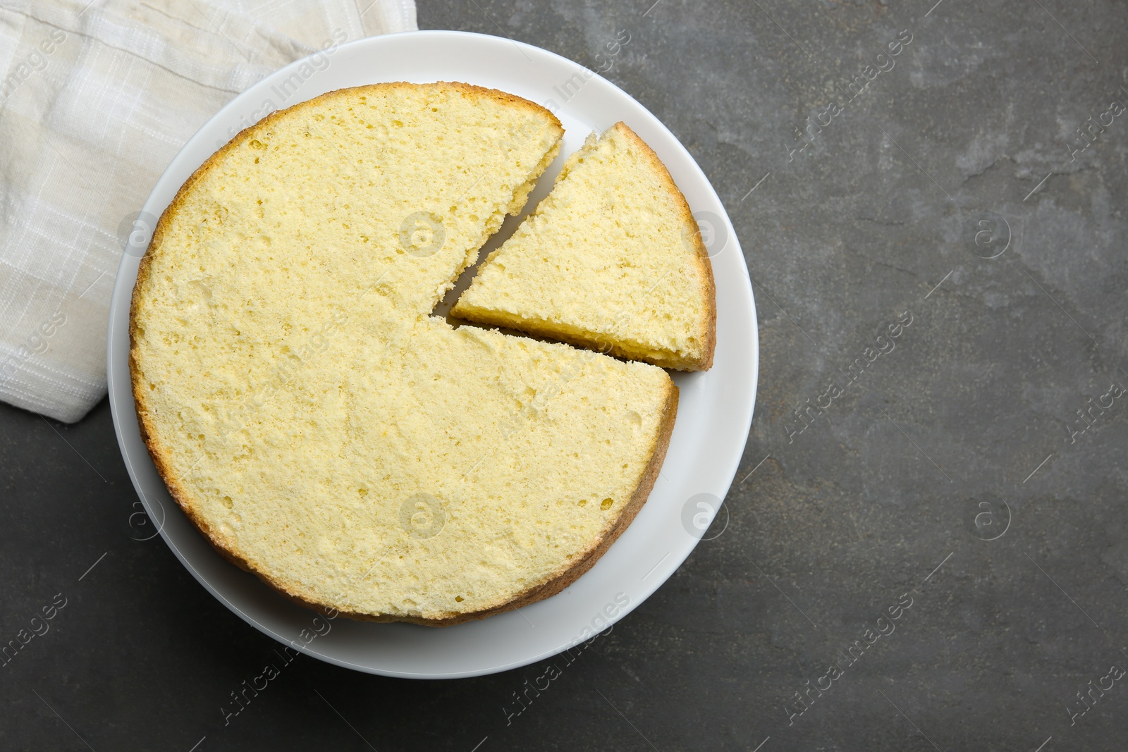 Photo of Delicious cut sponge cake on grey textured table, top view. Space for text