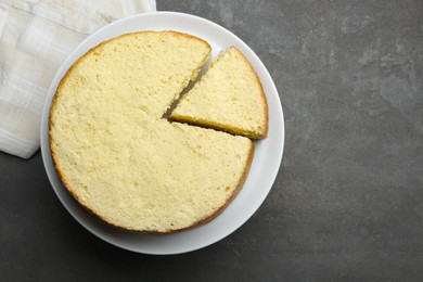 Photo of Delicious cut sponge cake on grey textured table, top view. Space for text