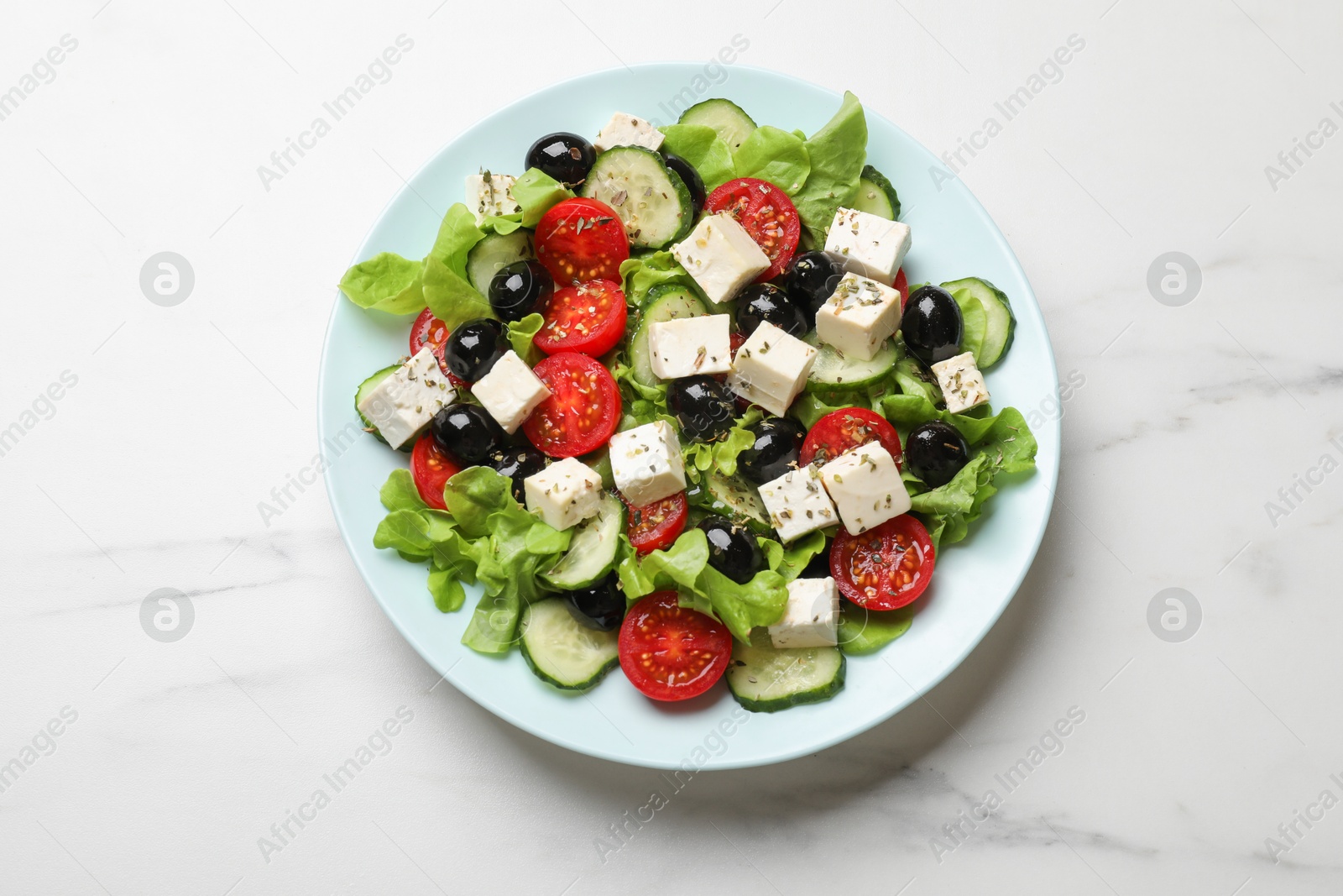 Photo of Delicious salad with feta cheese on white marble table, top view